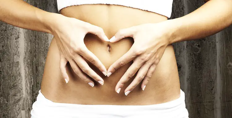Woman making a heart with her fingers over her belly
